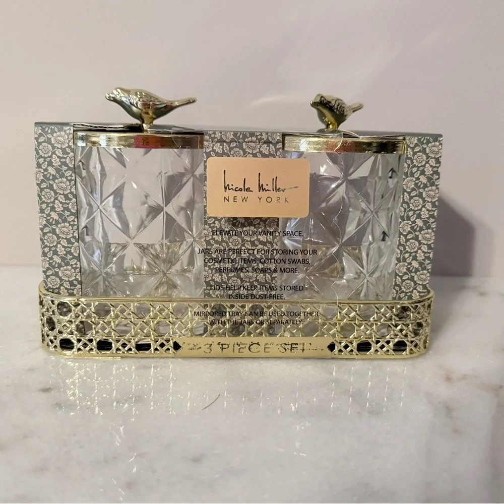 two-piece glass storage jar set with a gold bird lid and decorative tray.